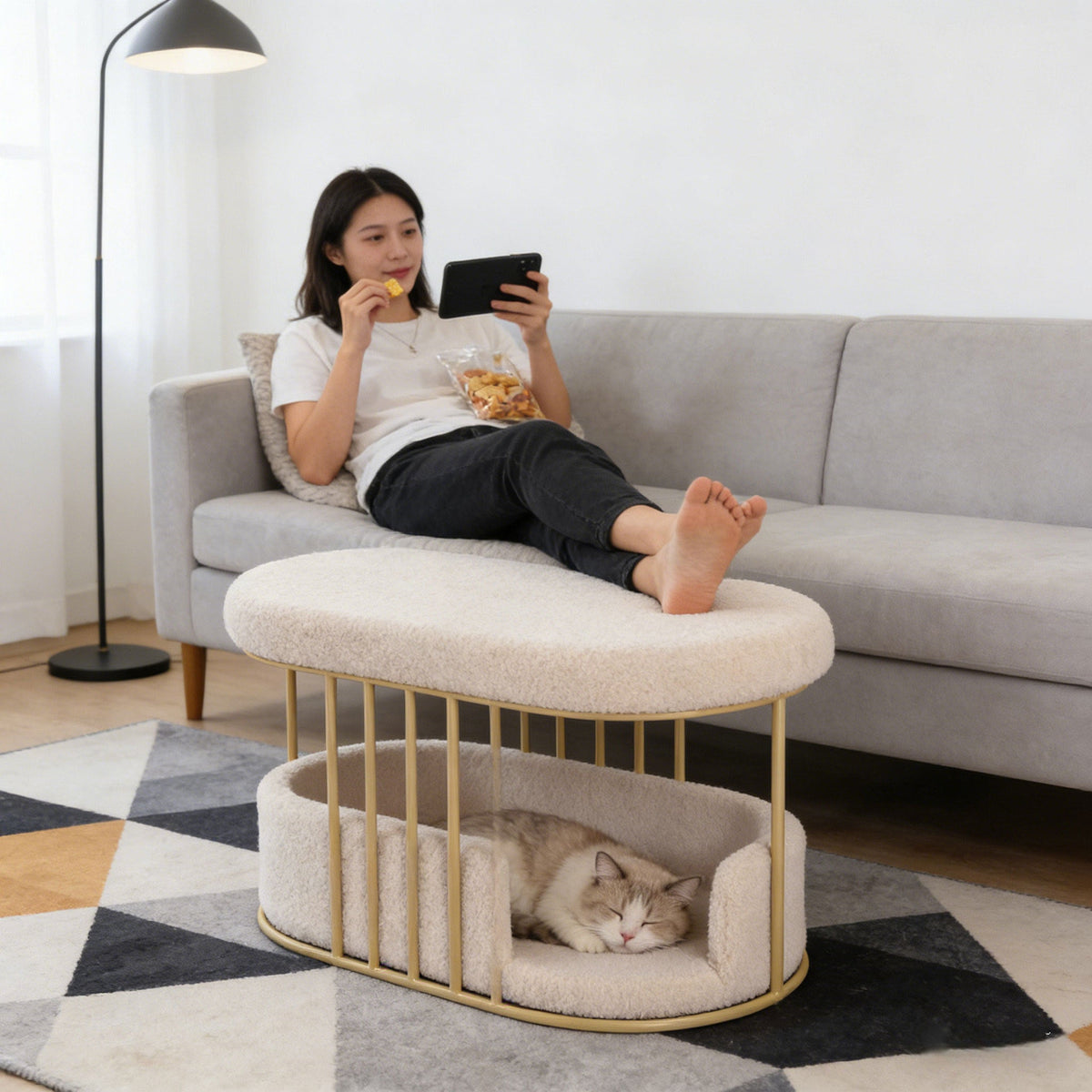 Cat sleeping in a bed under a bouclé ottoman in a living room